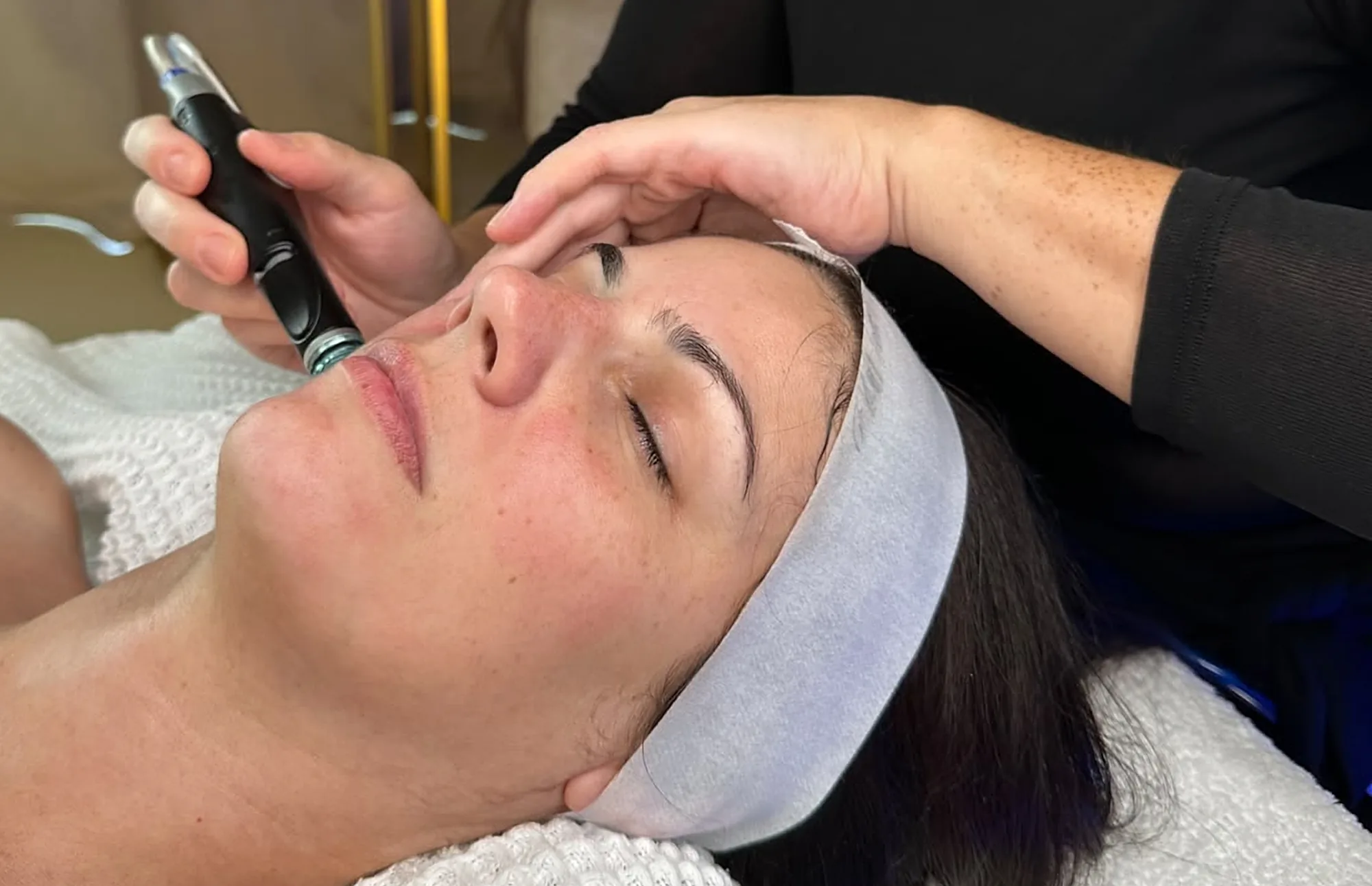 Les mains d'Imen pendant un soin du visage au stylo, sur une cliente allongée